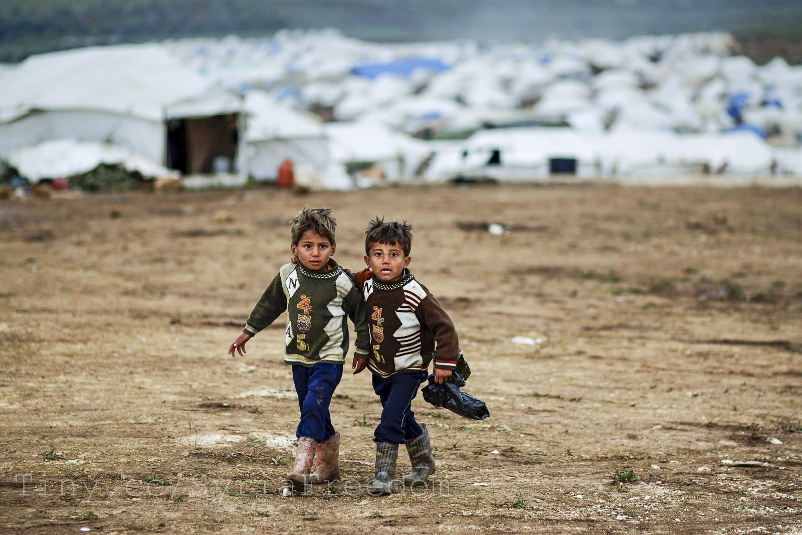 Syrian boys, whose family fled their home in Idlib, walk to thei