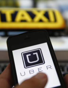 An illustration picture shows the logo of car-sharing service app Uber on a smartphone next to the picture of an official German taxi sign