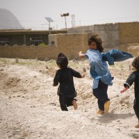 Afghan_children_play_near_U.S._military_on_patrol_(4665782053)