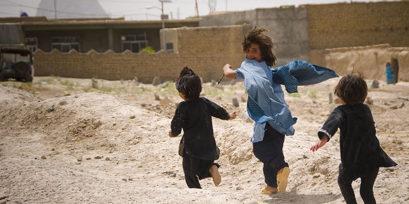Afghan_children_play_near_U.S._military_on_patrol_(4665782053)